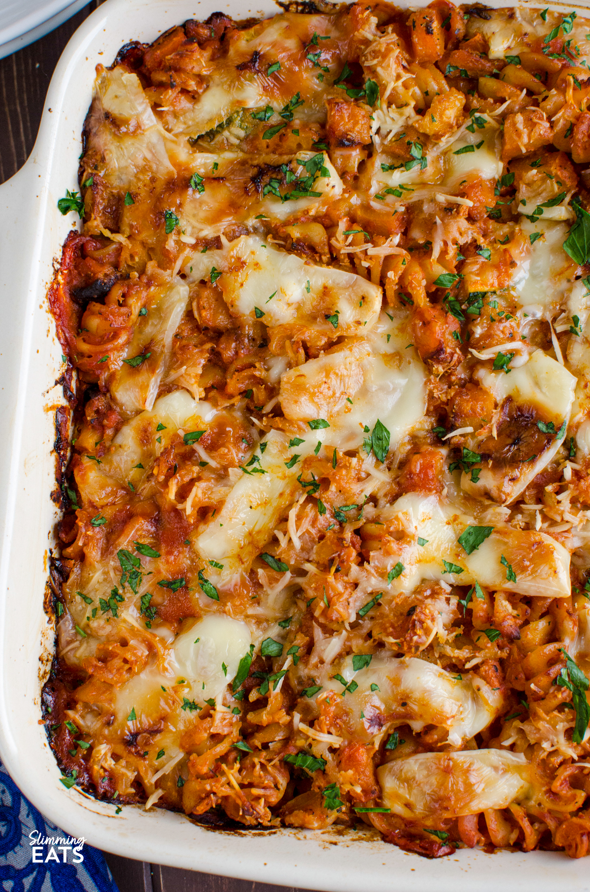 Roasted Butternut Squash Zucchini Pasta Bake - a simple comforting pasta bake with roasted butternut squash, zucchini and pasta baked in a tomato sauce with a delicious cheesy topping. It is an easy family friendly dinner that comes together with very little fuss and is perfect for busy evenings. close up of Roasted Butternut Squash Zucchini Pasta Bake in ceramic baking dish