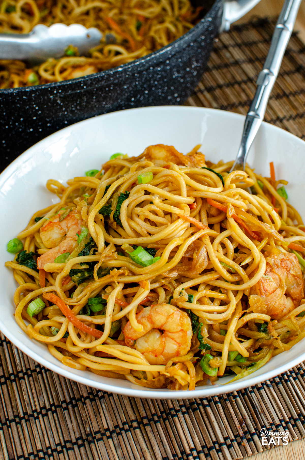 Sweet Chilli Prawn Noodles - an easy dinner that is packed with flavour and ready in less than 30 minutes. Juicy prawns, crisp vegetables and noodles are tossed together in a sweet, chilli sauce with just the right amount of heat for a quick meal that the whole family can enjoy. serving of Sweet Chilli Prawn Noodles in a white bowl wit fork