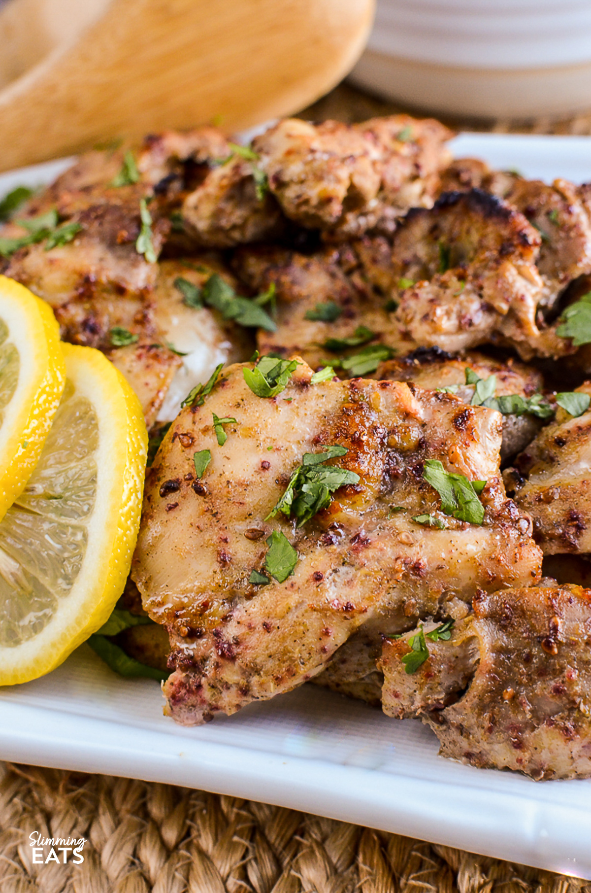 close up of Lebanese Chicken on white rectangle plate with lemon slices