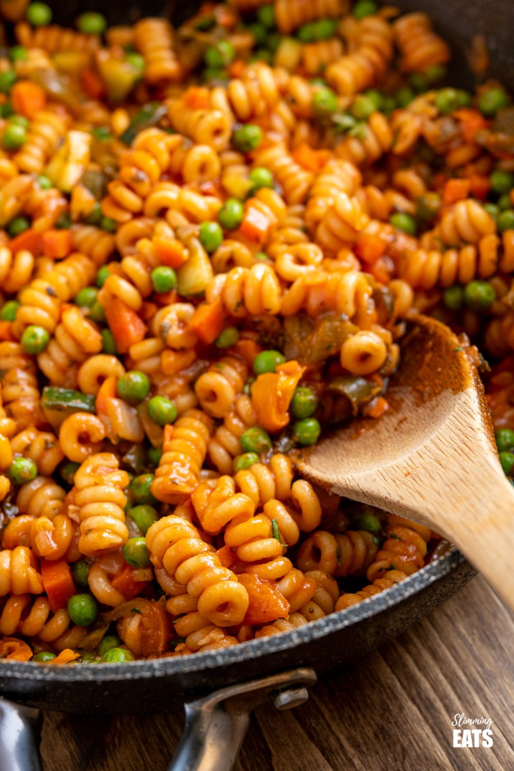 Delicious One Pot Speed Pasta - a perfect quick meal for the whole family to dig in enjoy. Dairy free, vegetarian, Slimming Eats and Weight Watchers friendly wooden spoon scooping one pot speed pasta out of frying pan