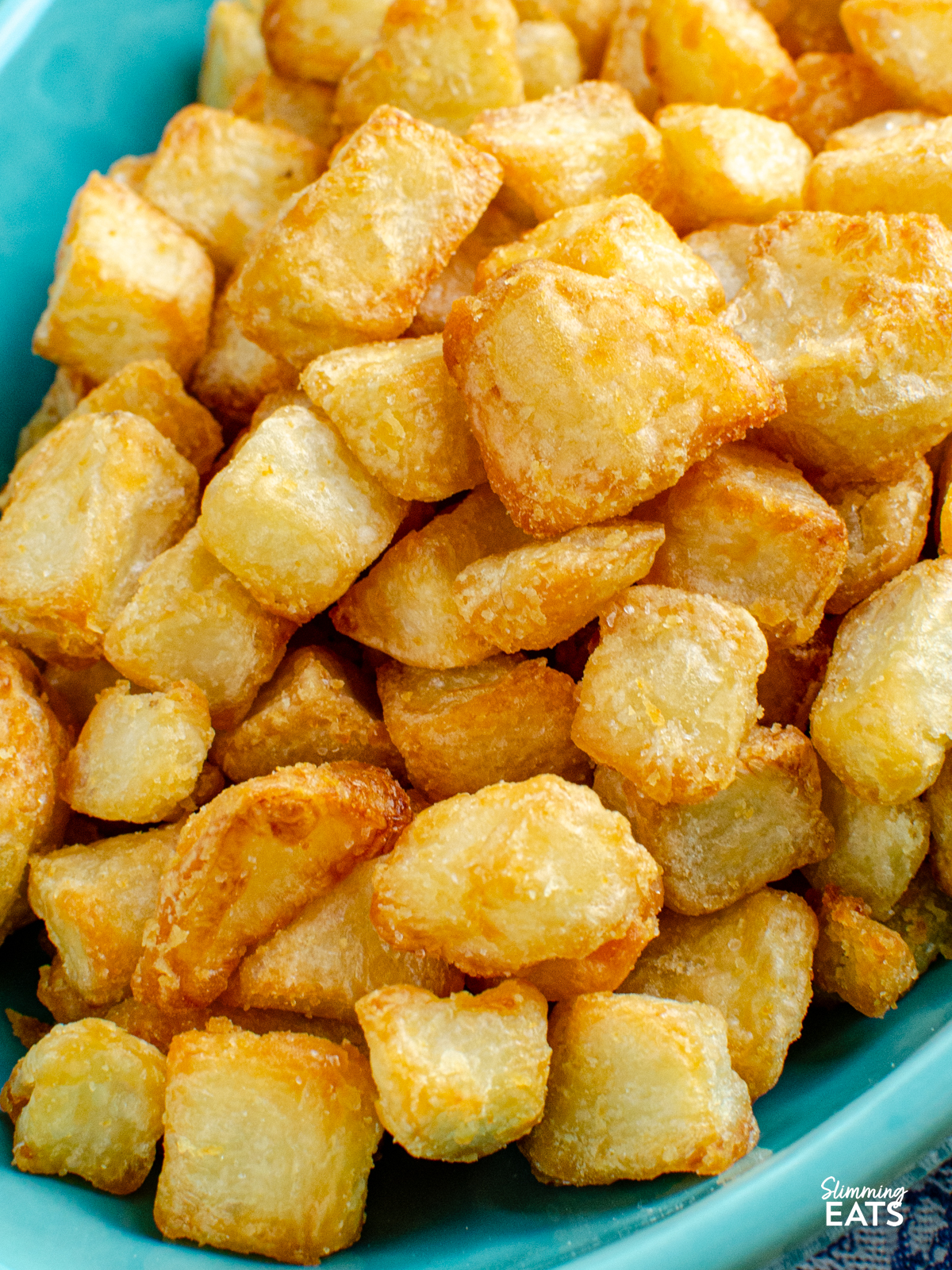 close up of extra crispy potatoes in a turquoise dish 