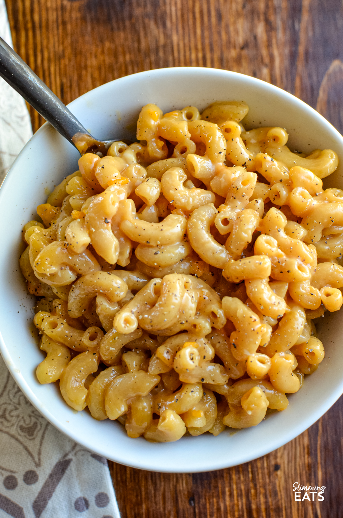 close up of marmite mac and cheese serving in a white bowl with fork