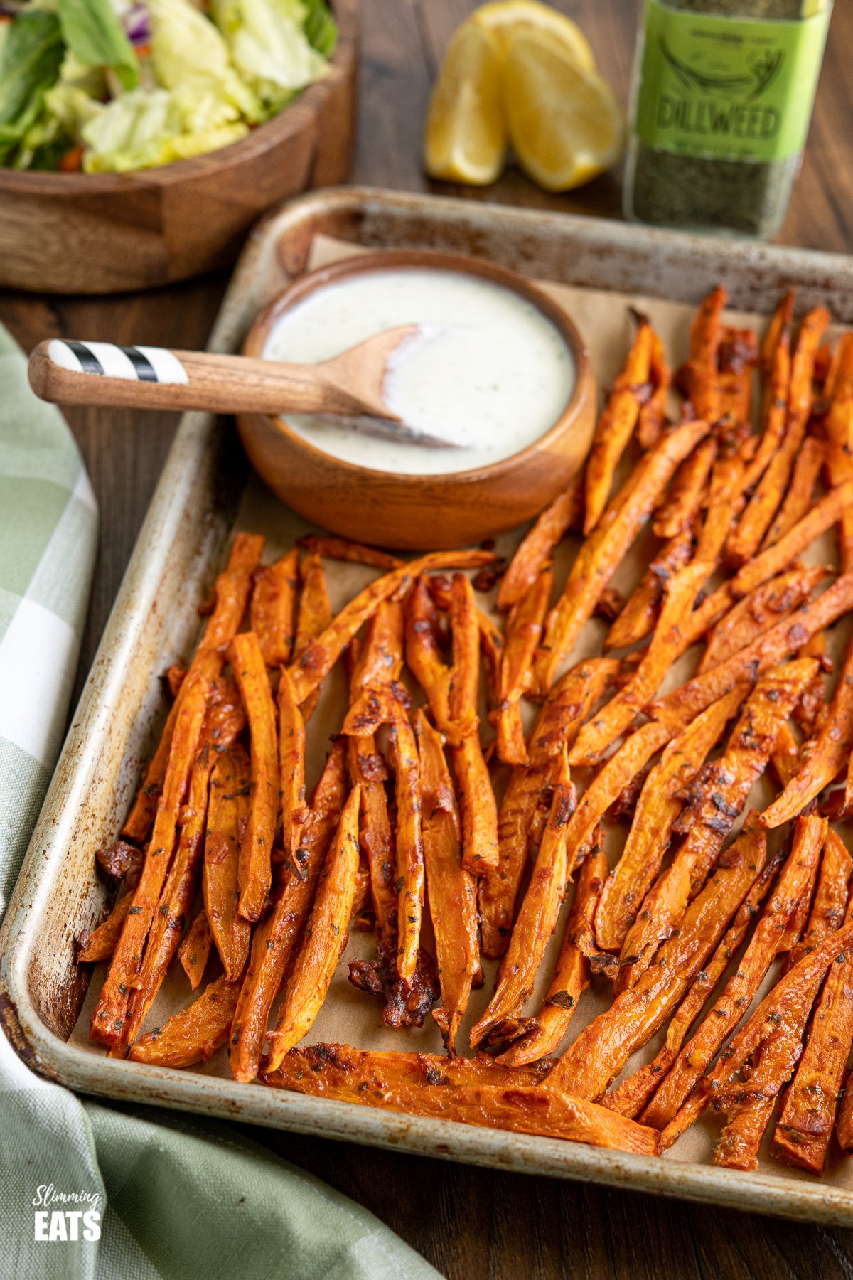 Parmesan Sweet Potato fries on a baking tray lined with parchment paper and with ranch dressing