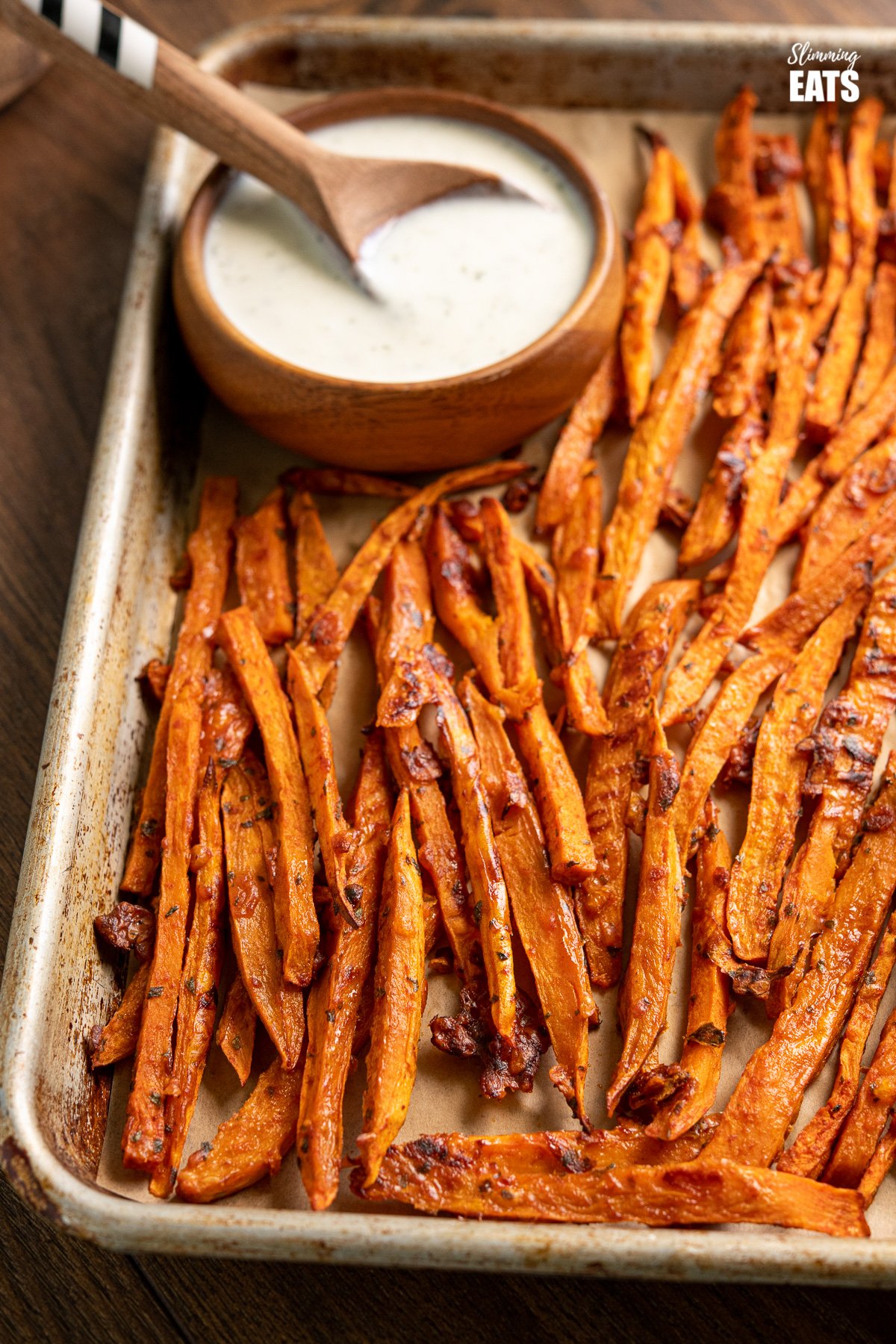 Parmesan Sweet Potato Fries with Ranch Dressing on baking tray with ranch dressing in wooden bowl