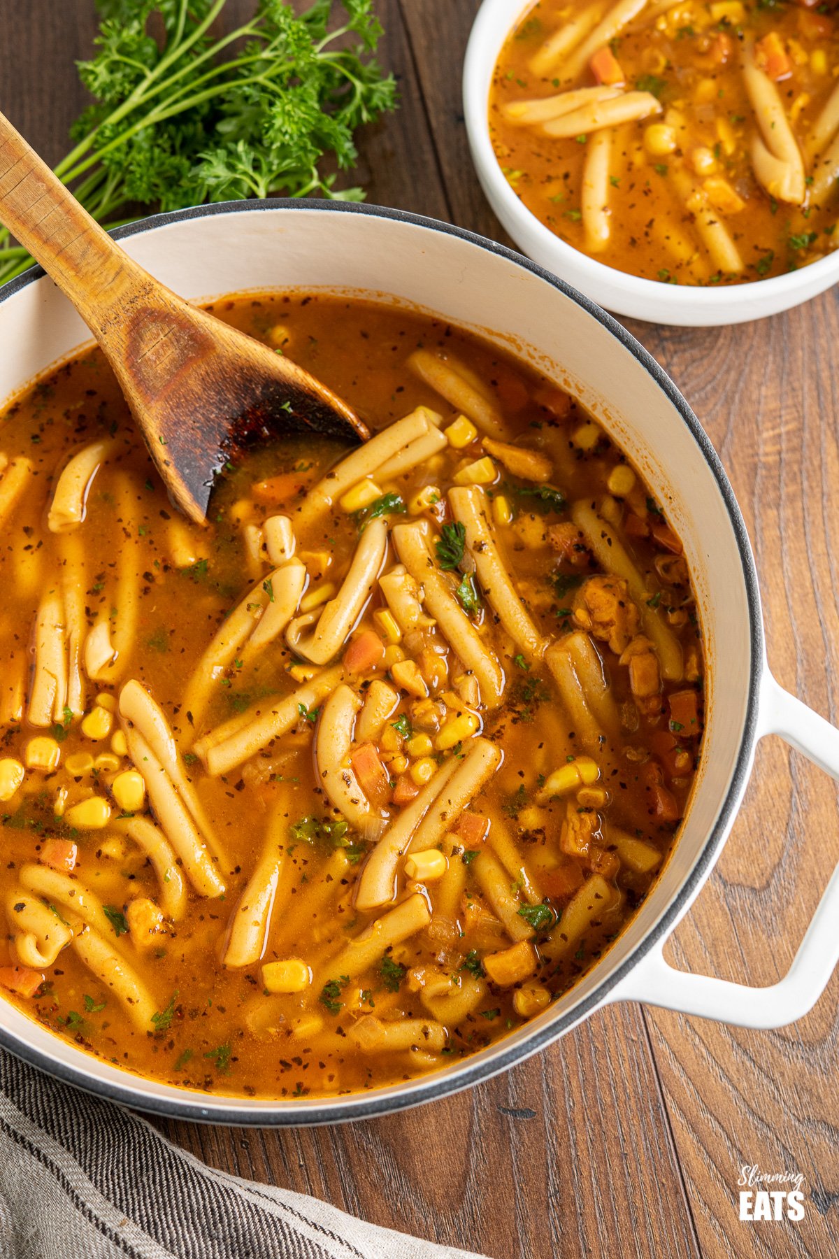 instant pot vegetable noodle soup in white cast iron pot with wooden spoon