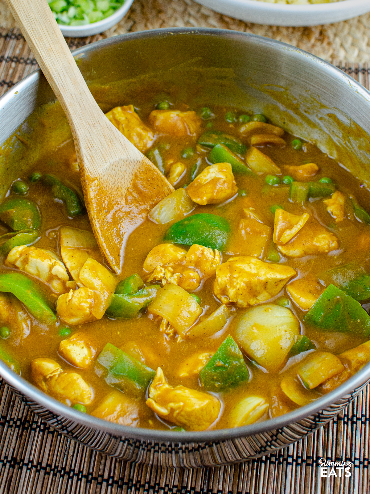 Chinese Chicken Curry in stainless steel frying pan with wooden spoon