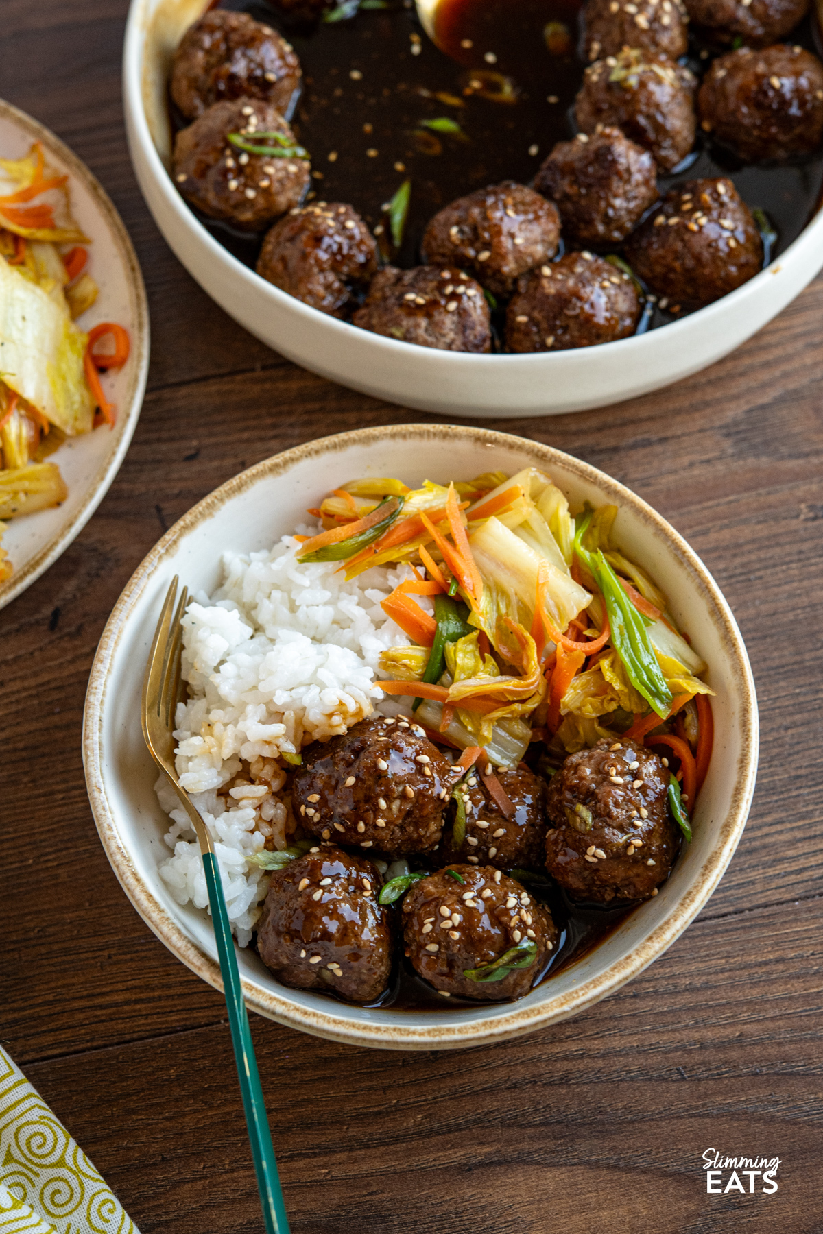 serving of Teriyaki Meatballs in a beige rimmed white bowl with stir fry veg and rice
