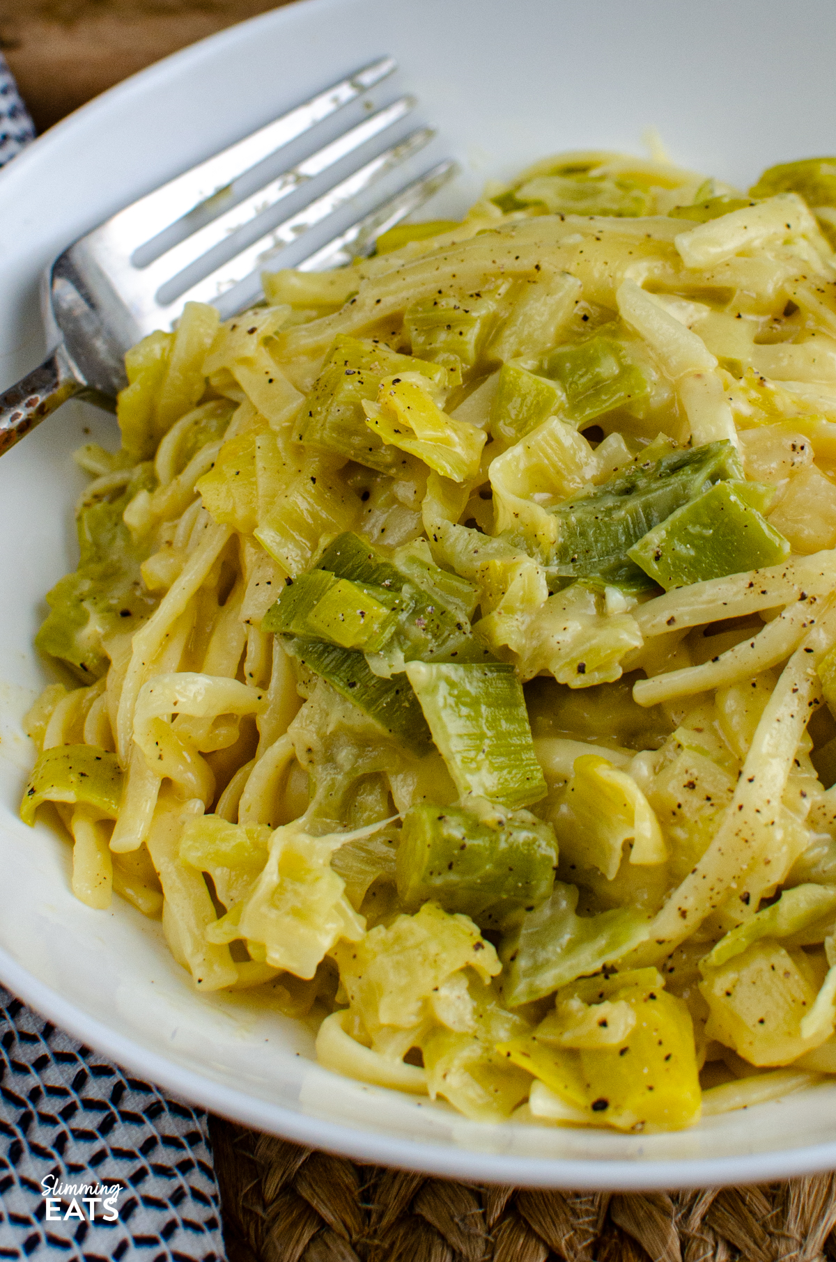close up of serving of Creamy Cheesy Leek Pasta in white bowl with fork