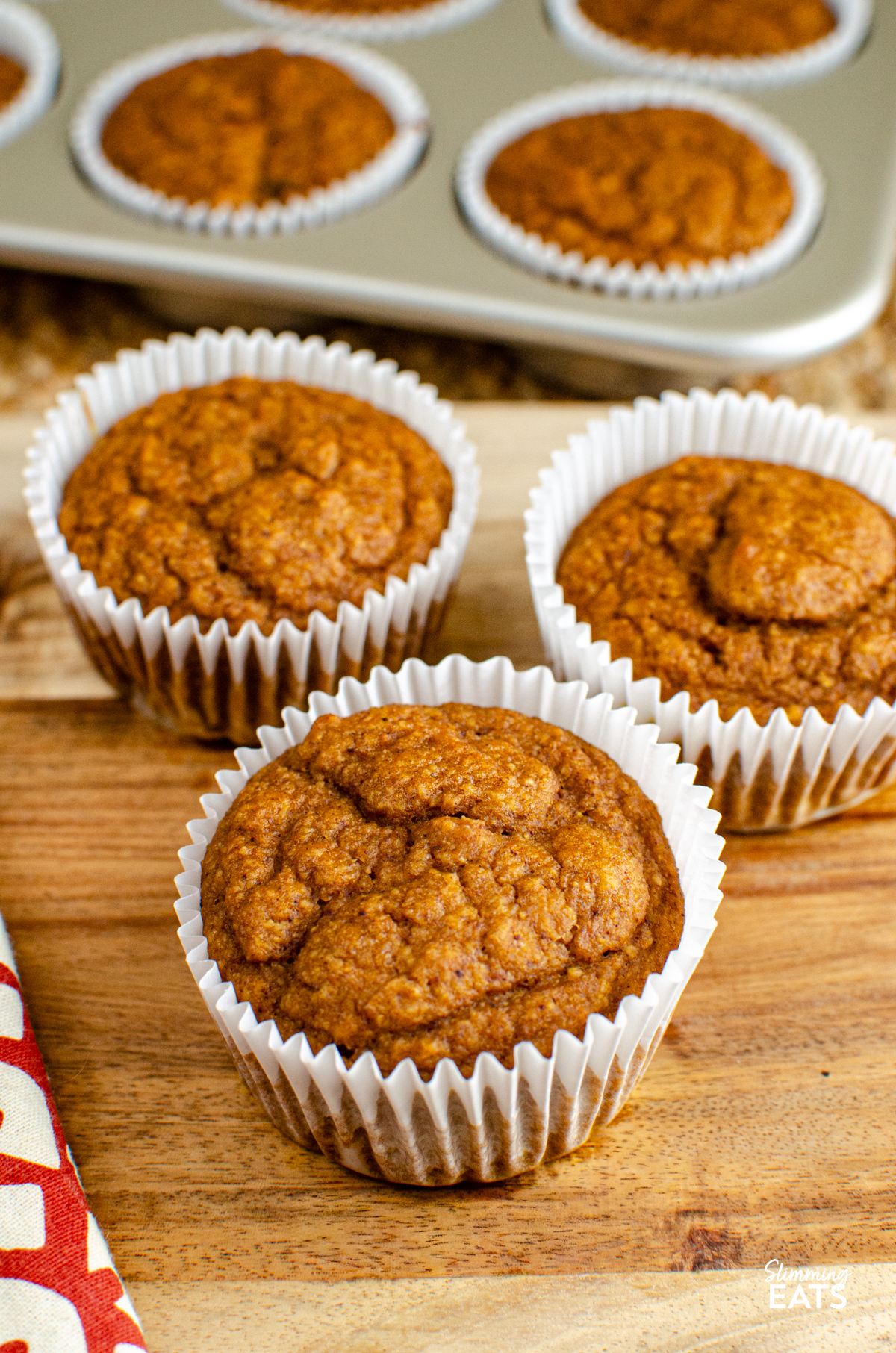 Pumpkin Sultana Muffins baked in muffin cases on a wooden board