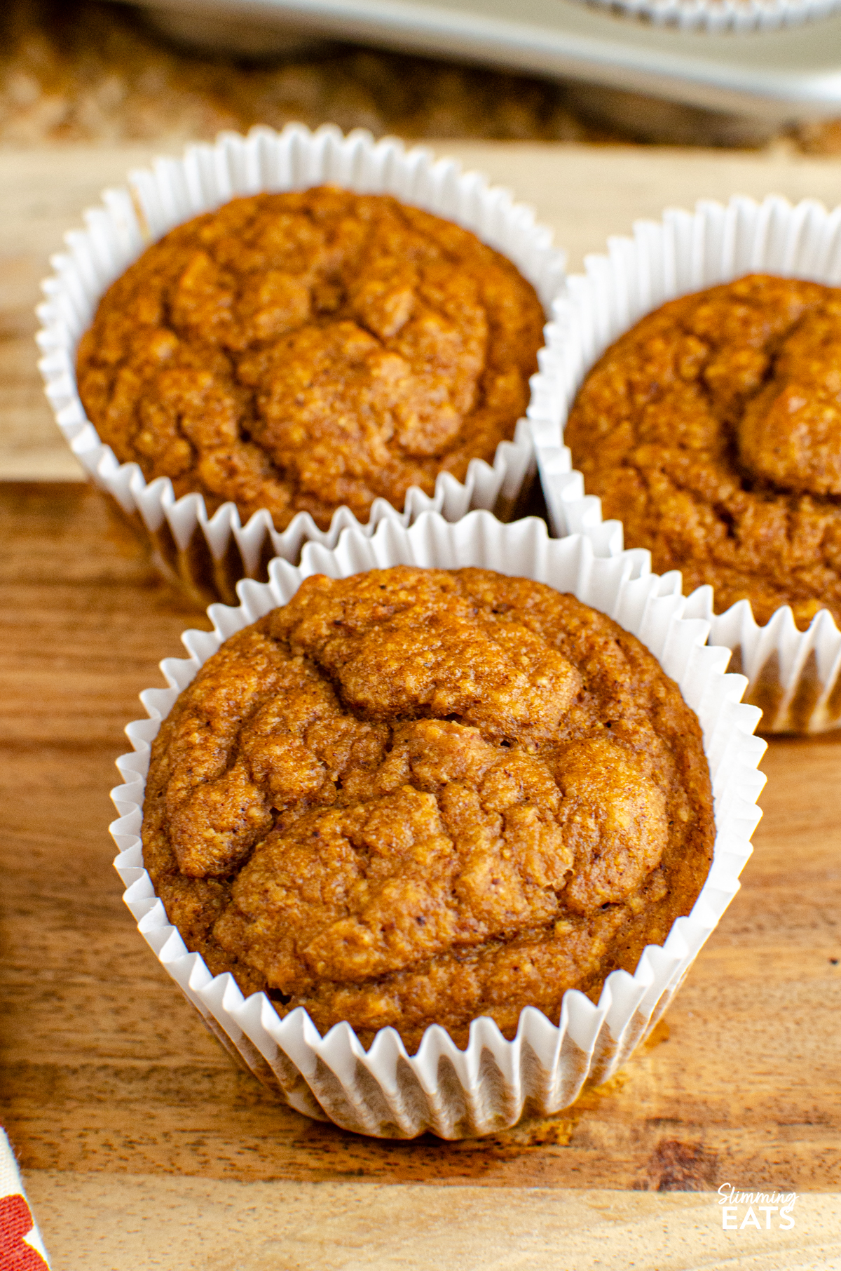  close up of Pumpkin Sultana Muffins in muffin cases on a board