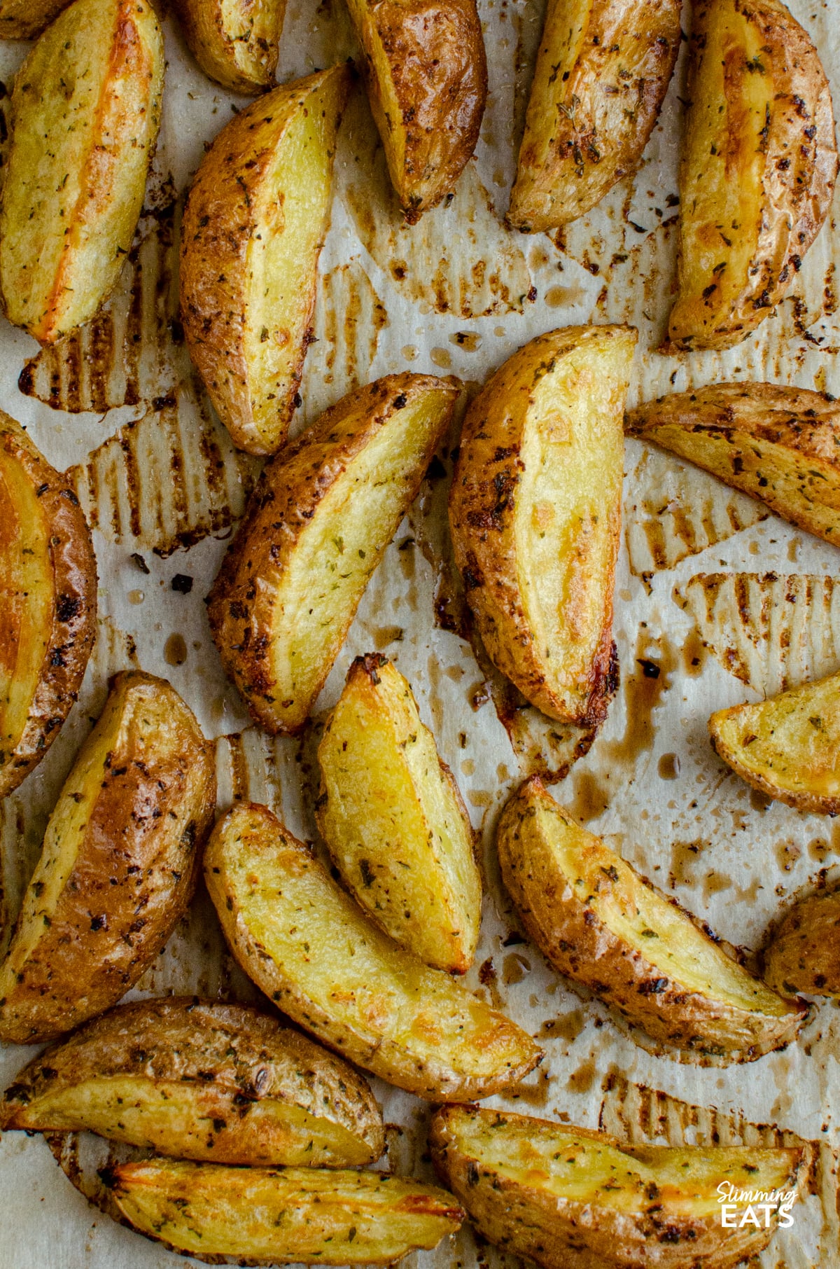 Tuck into these tasty Garlic and Herb Potato Wedges, a perfect side dish to round out just about any meal, and without the guilt too. Crispy on the outside, fluffy in the middle, they’re everything you want from a good wedge and so easy to make at home. Garlic and Herb Potato Wedges on parchment lined tray