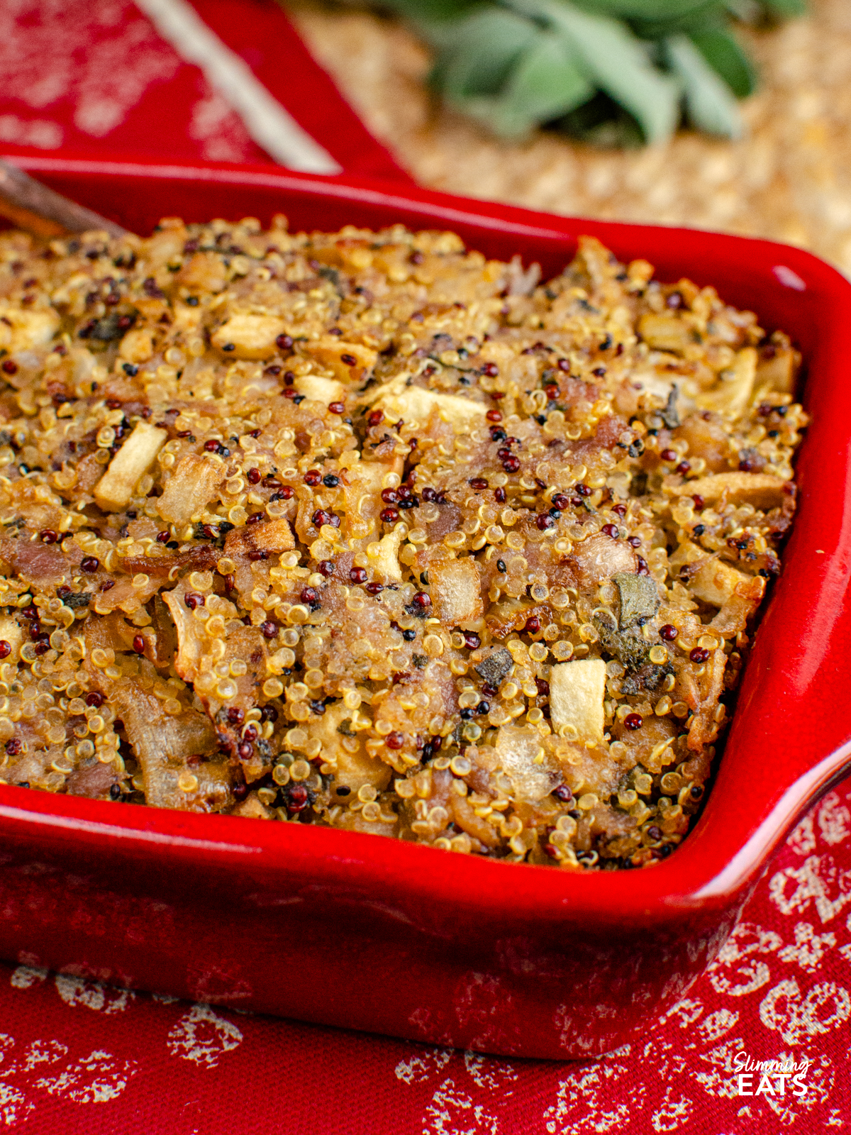 Sausage Sage Onion Quinoa Stuffing in a red ceramic dish, placed on a red and beige mat