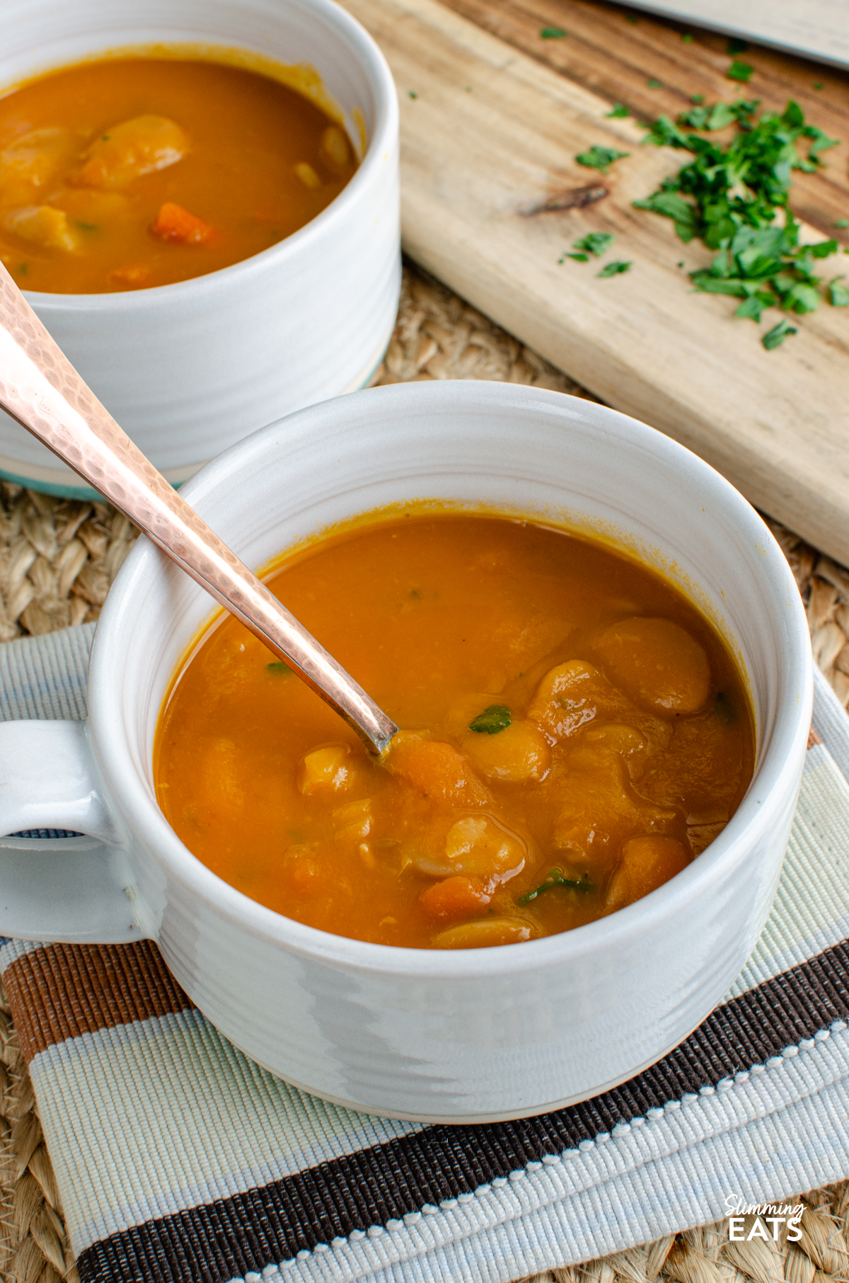 Carrot and Butter Bean Soup - a simple comforting soup with sweet carrots and creamy butter beans blended into a smooth flavour packed bowl that is perfect for lunch or a light dinner. It is quick to make, filling and delicious served with some warm crusty bread on the side. Carrot and Butter Bean Soup in a white with turquoise bottom soup mug with spoon