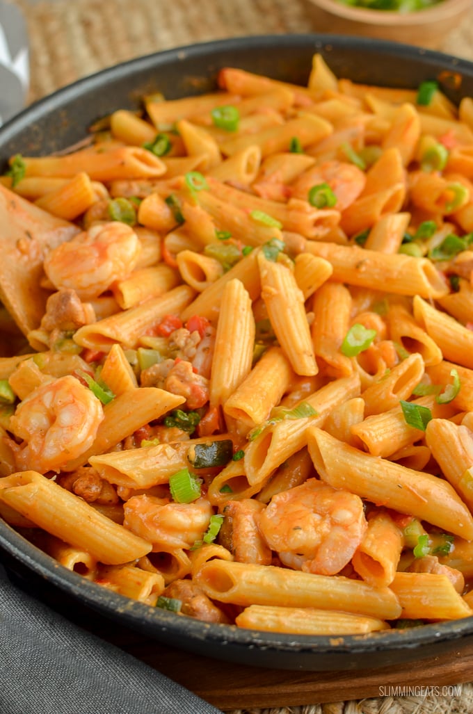 New Orleans Cajun Pasta in frying pan with wooden spoon - shrimp, chicken and pasta visible in pan.