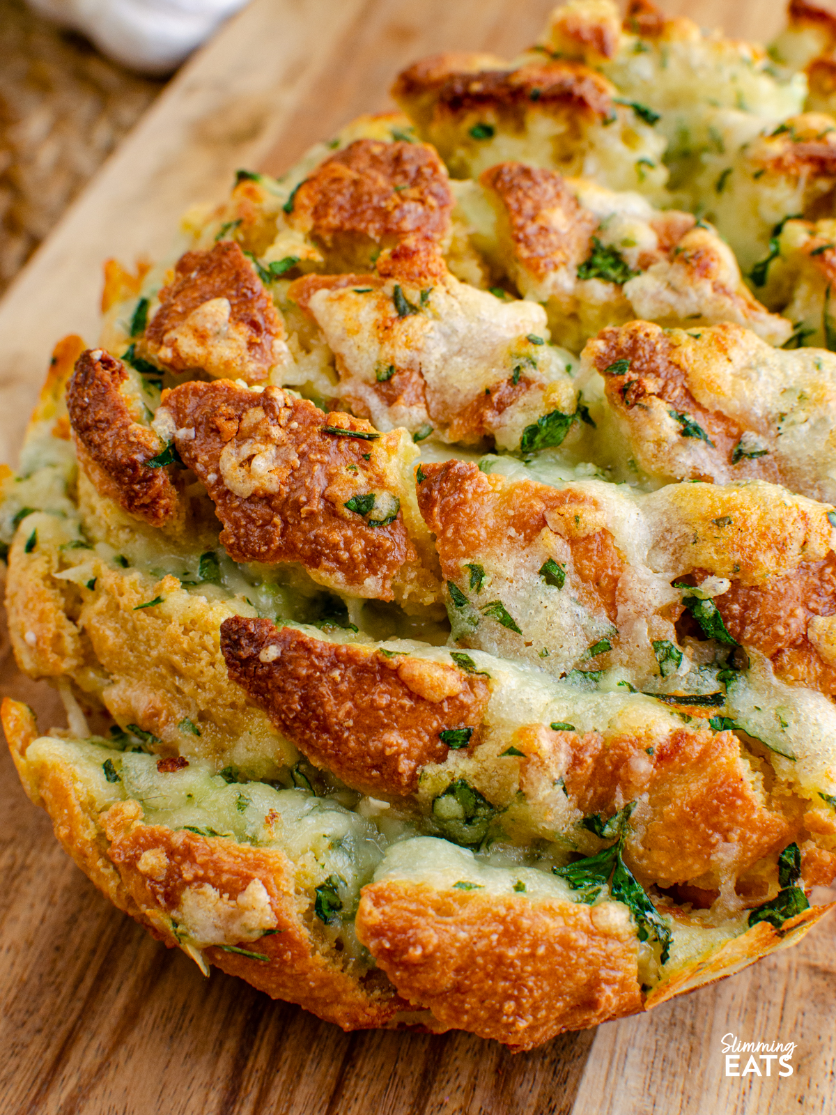 out of oven cheesy oat garlic bread on a wooden board