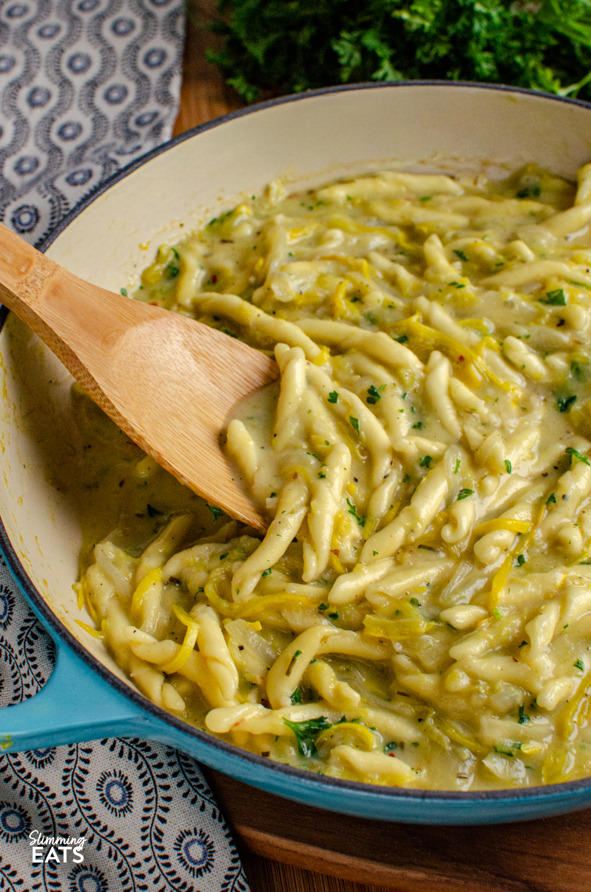 Dairy Free Yellow Zucchini Pasta - a creamy comforting one pot pasta dish made with simple ingredients and completely dairy free. Sweet yellow zucchini, garlic and pasta come together in a silky sauce, with light coconut milk adding that delicious creamy texture without needing any cheese or cream. One Pot Dairy Free Creamy Yellow Zucchini Pasta in a blue ceramic cast iron skillet with wooden spoon