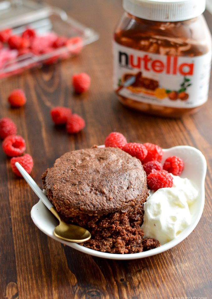 gluten free microwave chocolate cake in a mug with raspberries and cream with spoon and Nutella