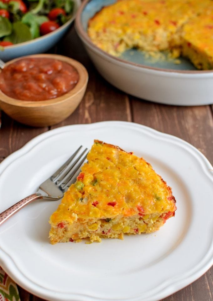 slice of lentil cheddar sweetcorn bake on plate with salad and salsa