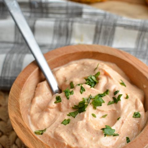 Louisiana remoulade dip in wooden bowl with patties in background with spoon