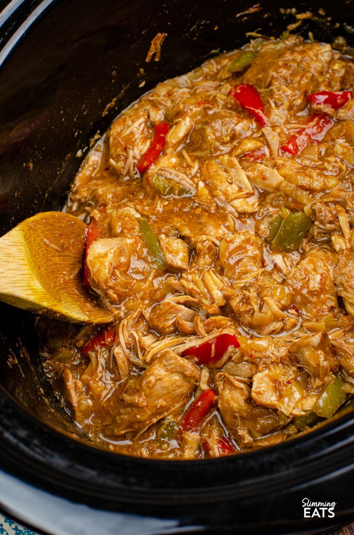 Slow Cooker Pineapple Pork - tender slow cooked pork in a delicious sweet and savoury sauce with pineapple, peppers, soy sauce and a little kick of spice. It is the perfect easy dinner that is ideal for busy days when you want dinner ready and waiting for you when you get home. Pineapple Pork in slow cooker with wooden spoon