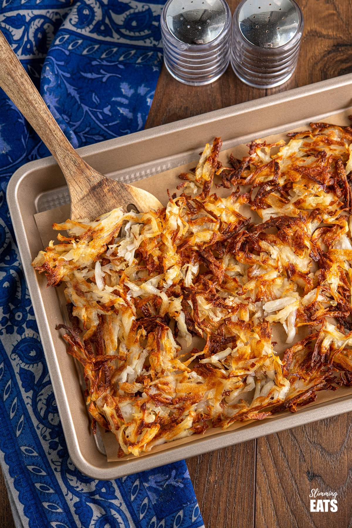 Sheet Pan American Crispy Hash Browns - the perfect side for when you fancy a filling breakfast and perfect with eggs, bacon or sausage. #potatoes #hashbrowns #slimming #weightwatchers #vegan #vegetarian #glutenfree #dairyfree crispy golden sheet pan hash browns on a baking tray with parchment