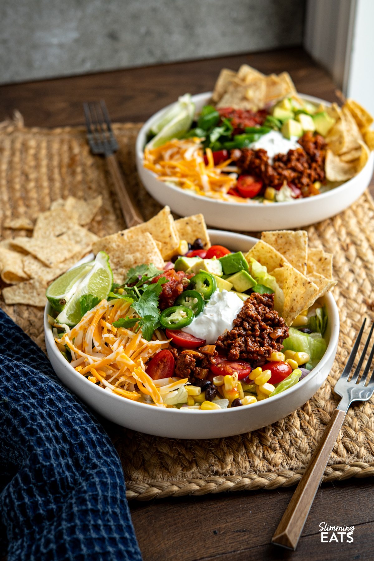 These Taco Salad Bowls are packed with all the delicious flavours of tacos, served over a fresh, colourful salad for an easy meal that is hearty, satisfying and perfect for lunch or dinner. plated up taco salad bowl with beans, corn, avocado, salsa, soured cream, onion, lettuce, tortilla chips, cheddar and jalapenos.