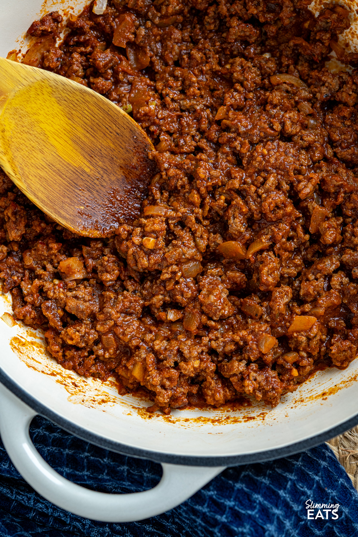 These Taco Salad Bowls are packed with all the delicious flavours of tacos, served over a fresh, colourful salad for an easy meal that is hearty, satisfying and perfect for lunch or dinner. cooked taco meat in a cast iron enameled skillet with wooden spoon