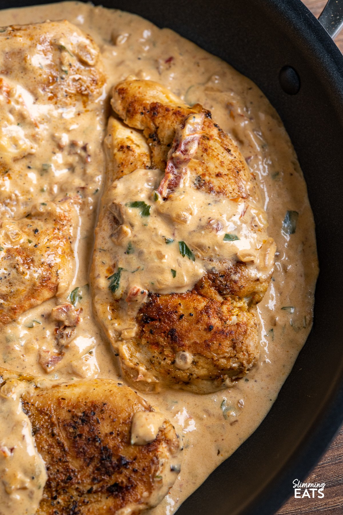Chicken in Creamy Sun-dried Tomato Sauce - This mouthwatering dish features tender and juicy chicken breasts smothered in a rich and tangy sauce made with low-fat cream cheese and sun-dried tomatoes. close up of Chicken in Creamy Sun-dried Tomato Sauce in pan