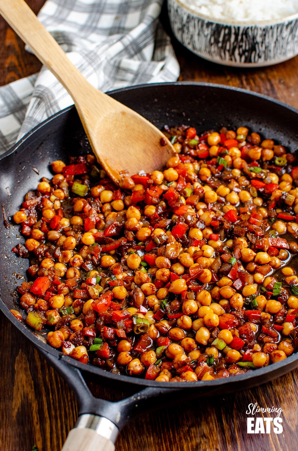 Chinese 5 spice Chickpeas in black frying pan with wooden spoon on board