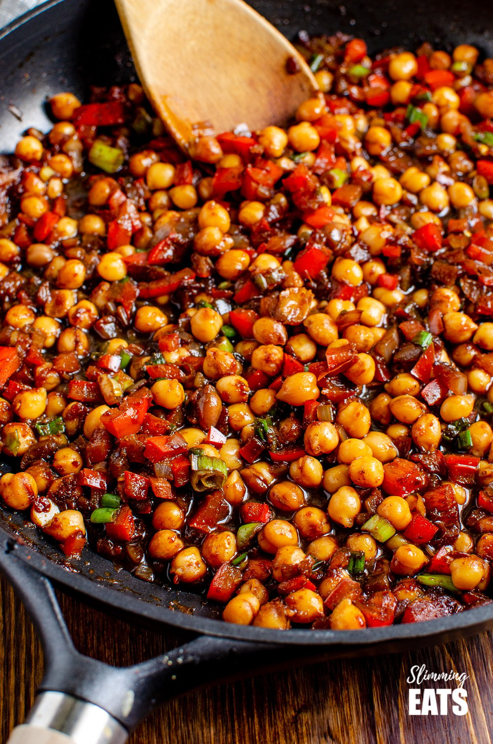 close up Chinese 5 spice Chickpeas in black frying pan with wooden spoon