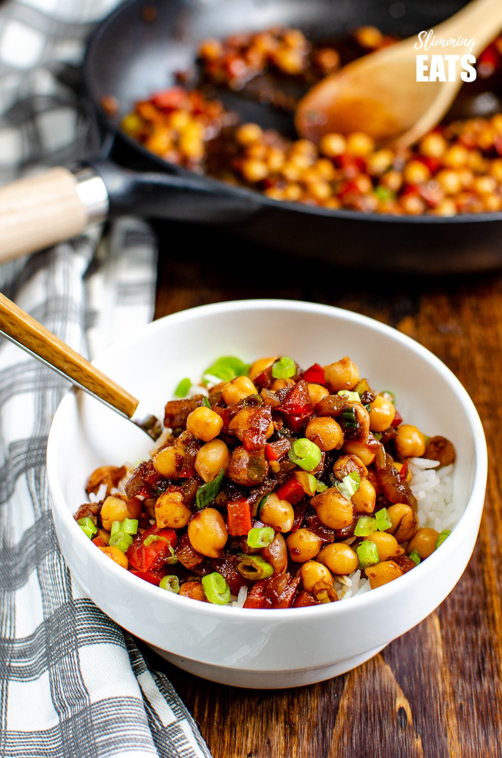 Chinese 5 spice Chickpeas in white bowl over rice with wooden handled spoon