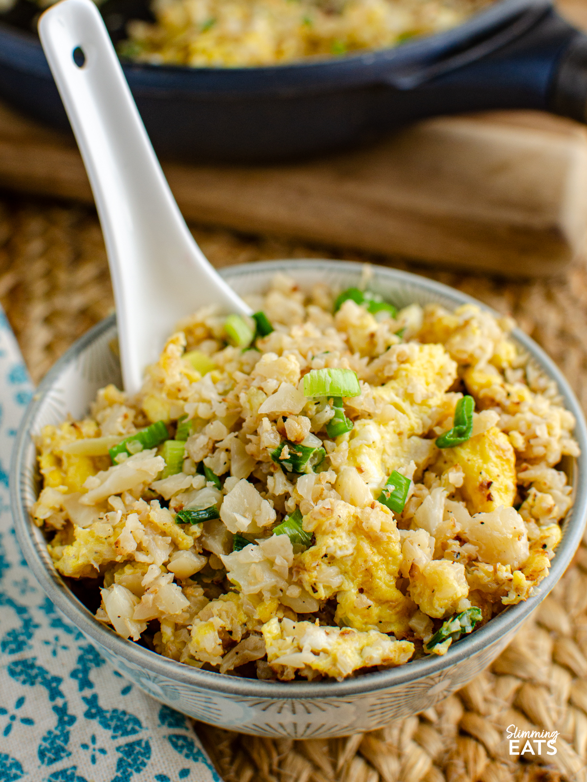 egg fried cauliflower rice in a small grey white patterned bowl with ceramic spoon