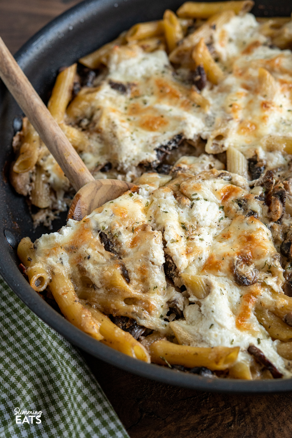 serving of Baked Garlic Mushroom and Ricotta Pasta on wooden spoon being scooped from frying pan