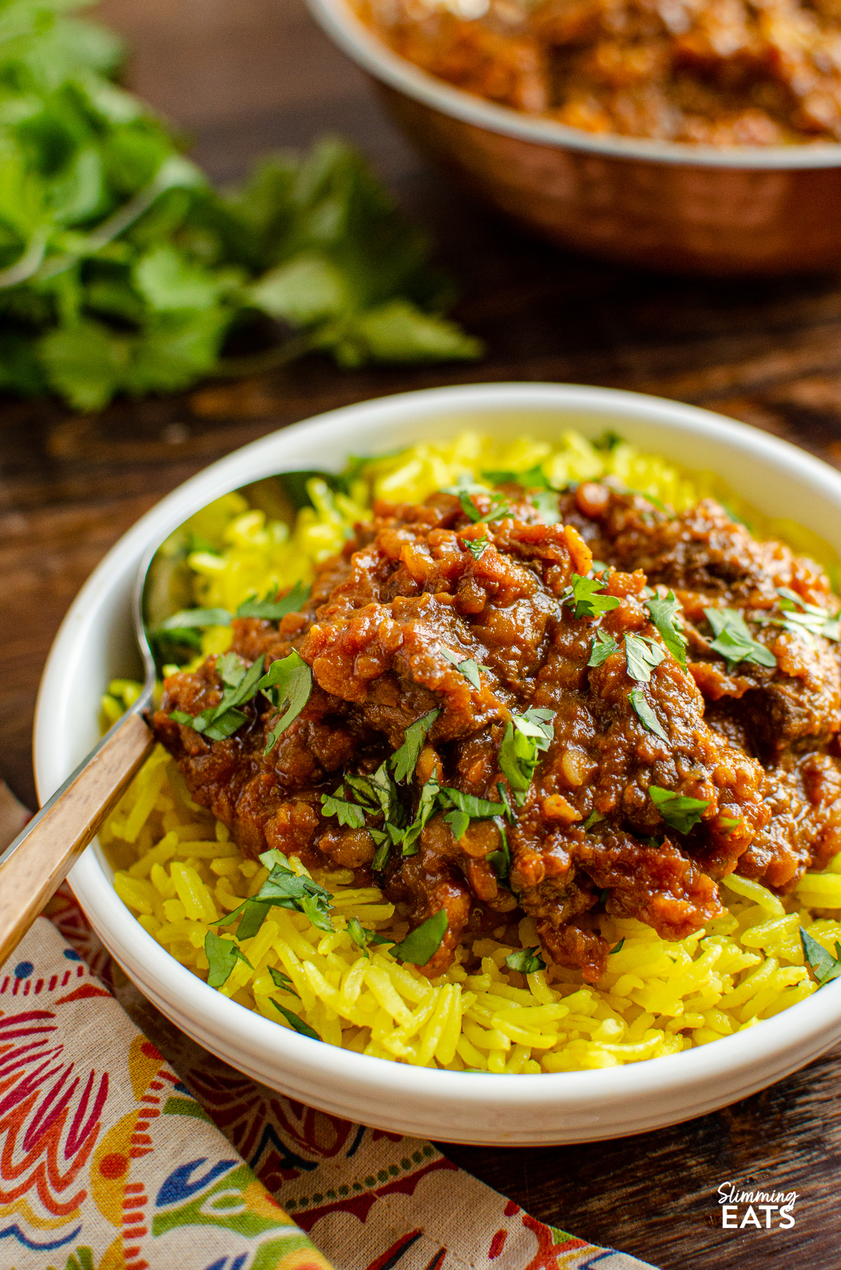Beef Dhansak in white bowl with pilau rice and scatter coriander