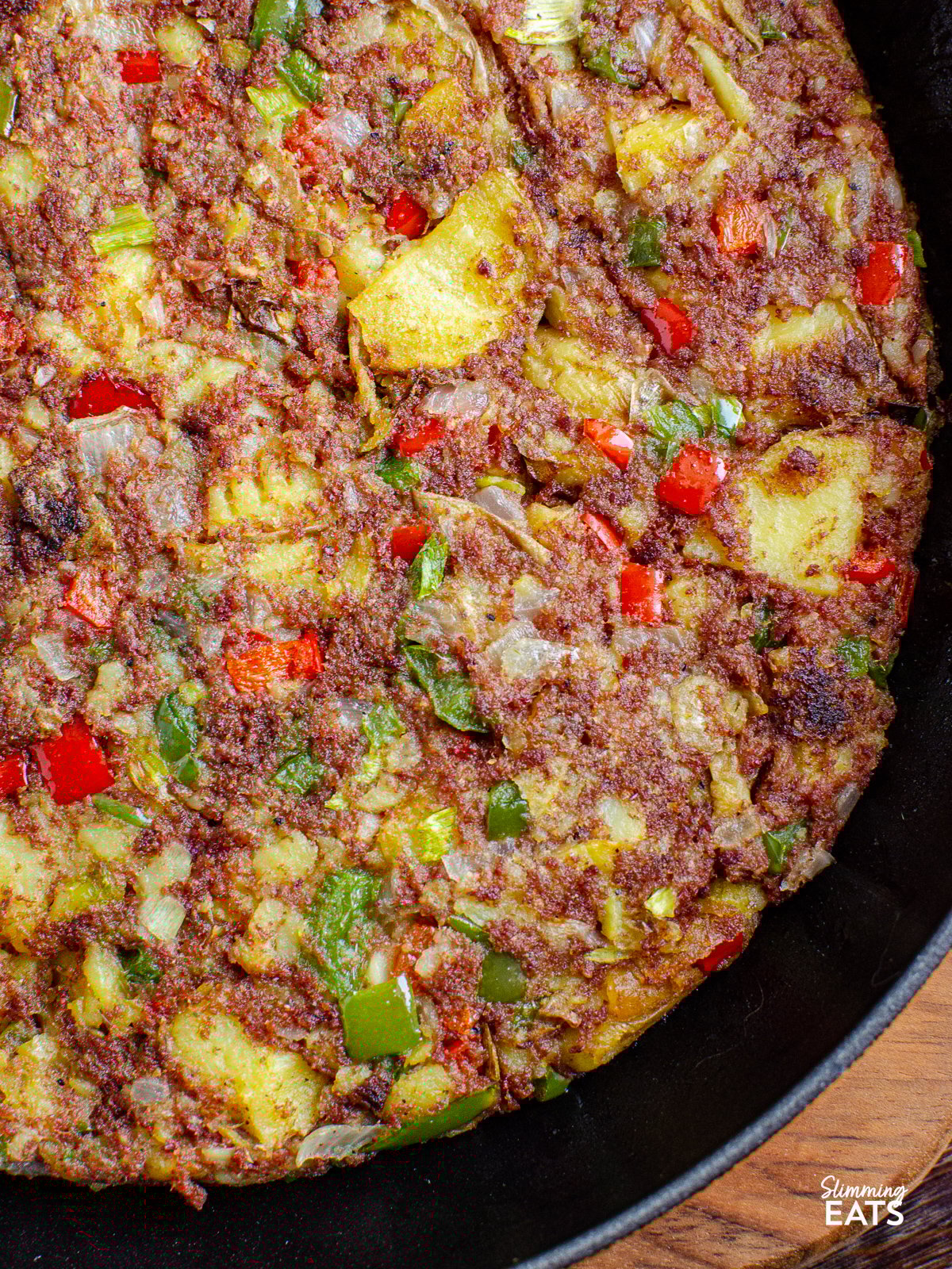Corned Beef Hash Skillet with peppers, onion and golden potatoes for an easy family friendly recipe that is perfect for breakfast, lunch or dinner close up of Corned Beef Hash in a cast iron orange Le Creuset skillet