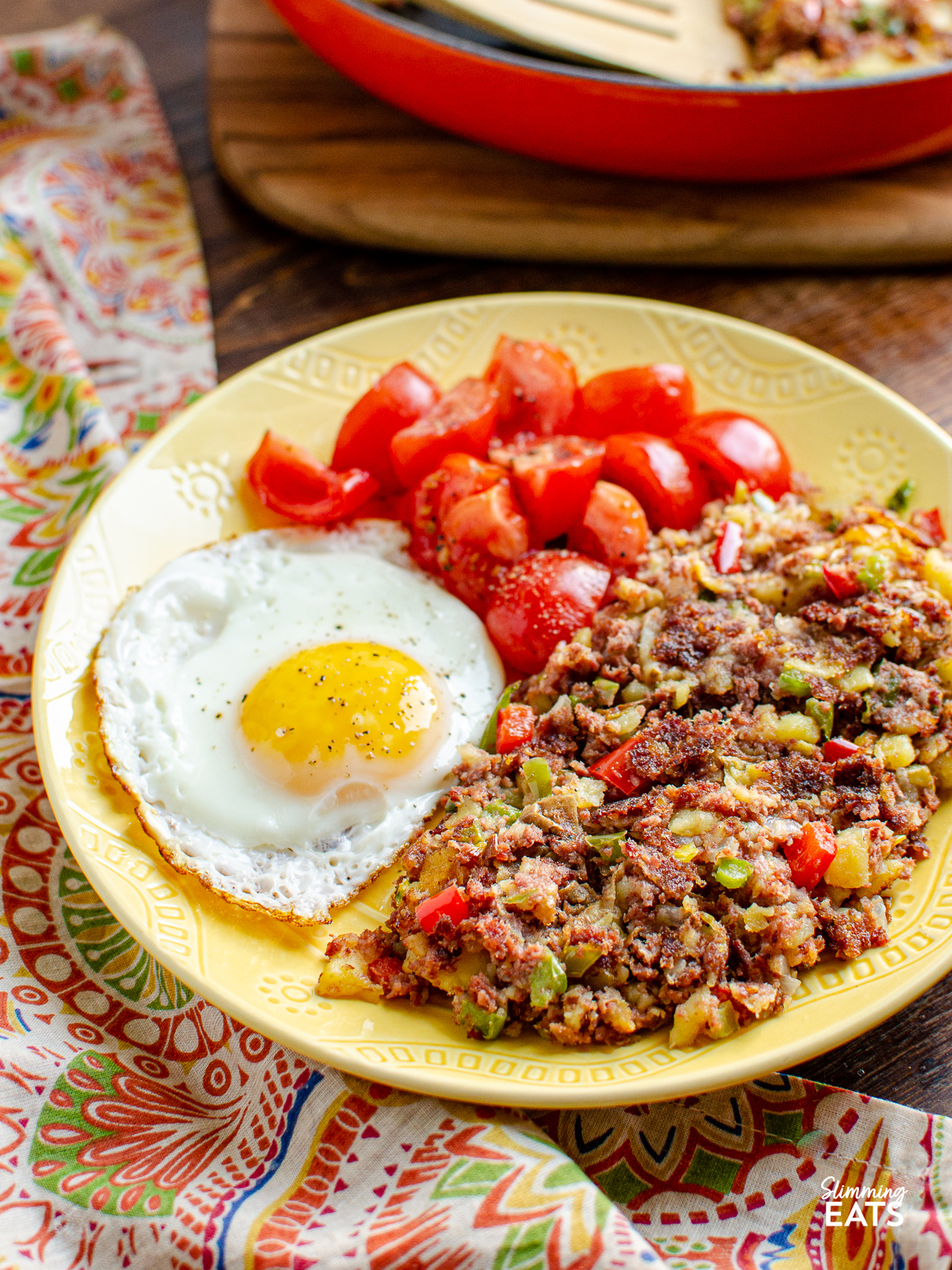 Corned Beef Hash  on a yellow plate with fried egg and ripe grape tomatoes