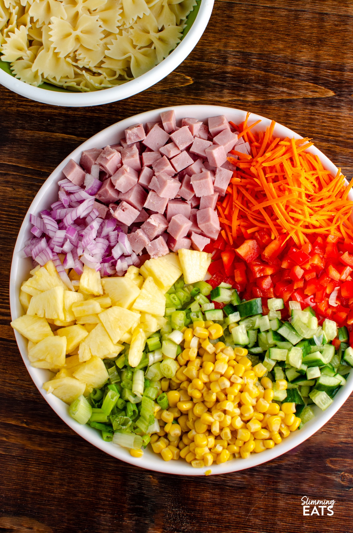 This Hawaiian Pasta Salad is a fresh, creamy and colourful side dish packed with ham, pineapple and crunchy vegetables, perfect for barbecues, picnics or easy lunches. all the ingredients for hawaiian pasta salad chopped and in a white bowl ready to be mixed.