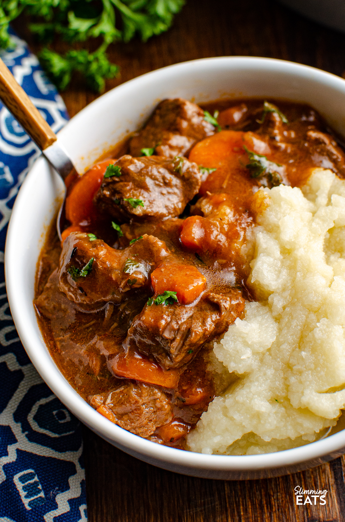 close up of braised beef in white bowl with cauliflower mash