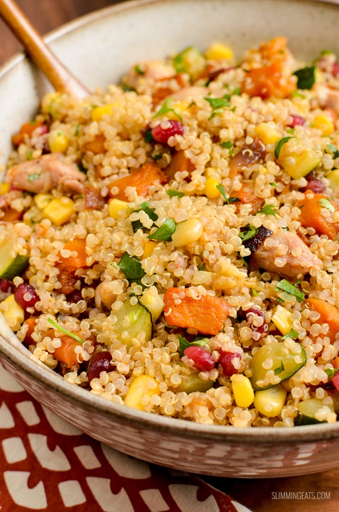 close up of Roasted Butternut Squash Chicken Quinoa Salad in beige bowl with pomegranate and zucchini