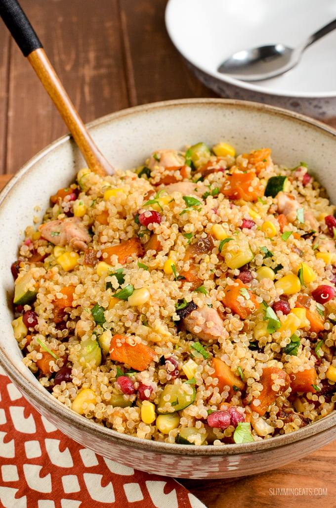 Roasted butternut squash chicken quinoa salad in large beige bowl with wooden spoon