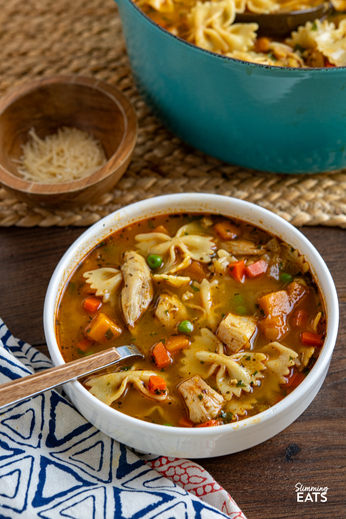serving of chicken vegetable pasta soup in bowl with spoon 