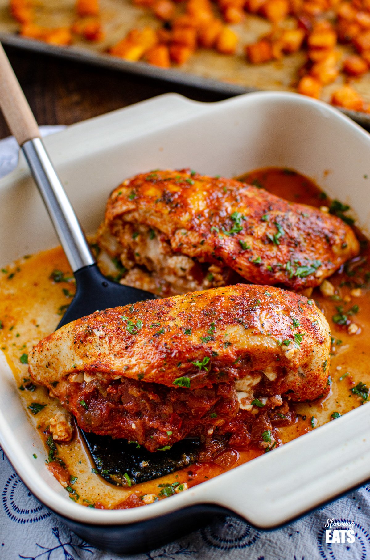 Spicy Chicken Stuffed with Feta Cheese and Salsa in baking dish with spatula