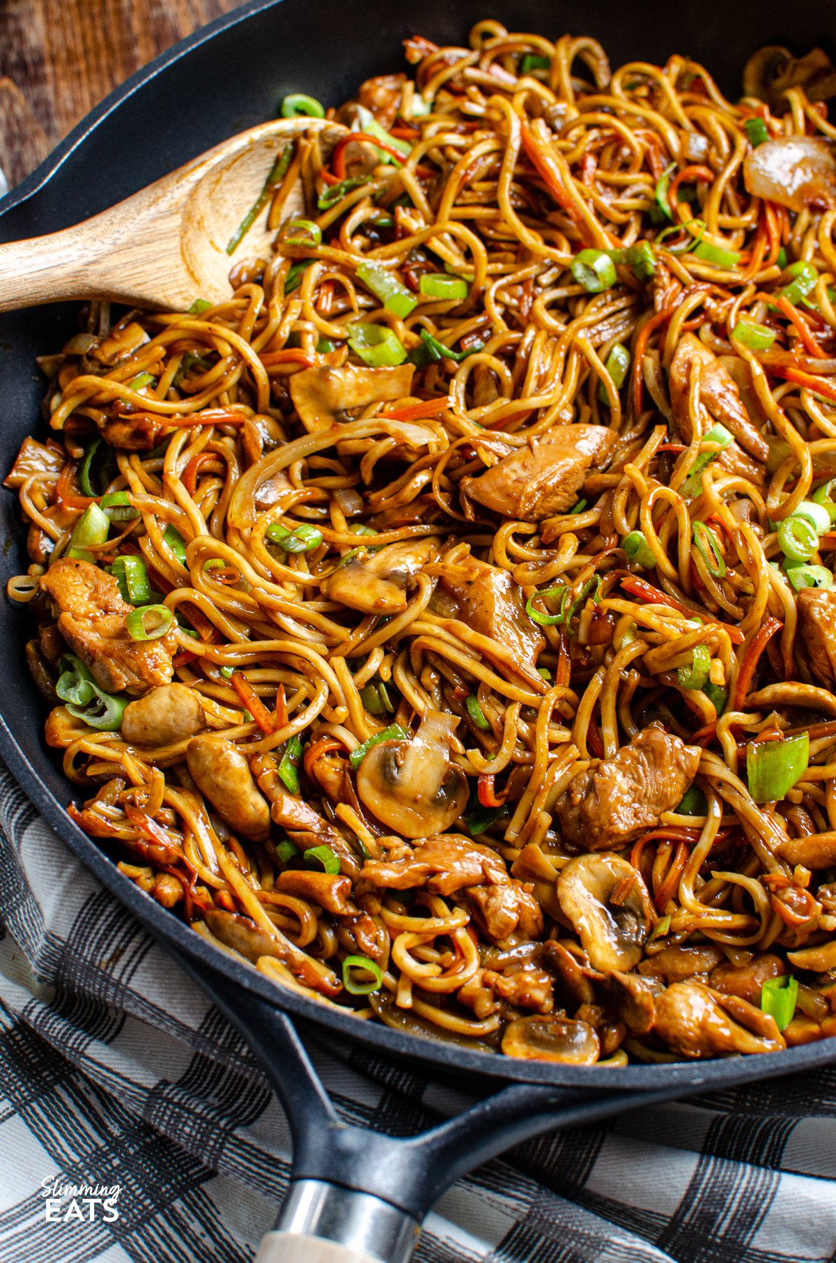 close up Ginger Chicken with Mushrooms and Noodles in a black frying pan