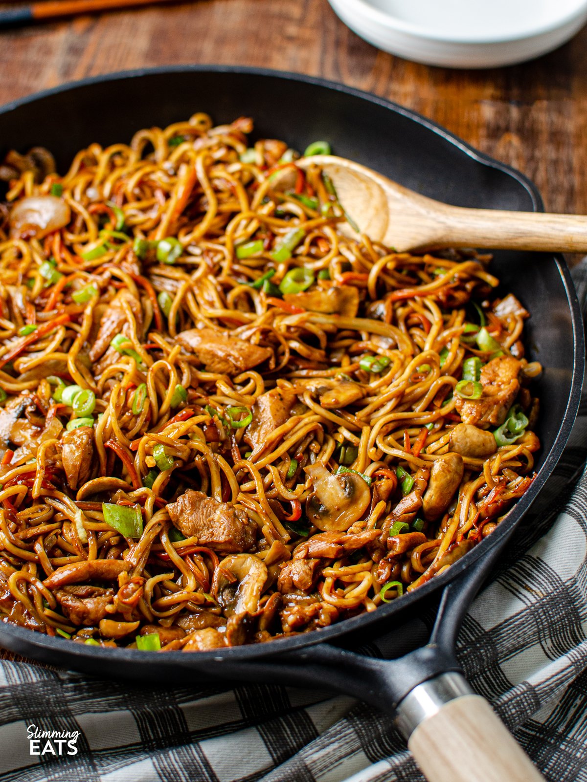 Ginger Chicken with Mushrooms and Noodles in a black frying pan with wooden spatula