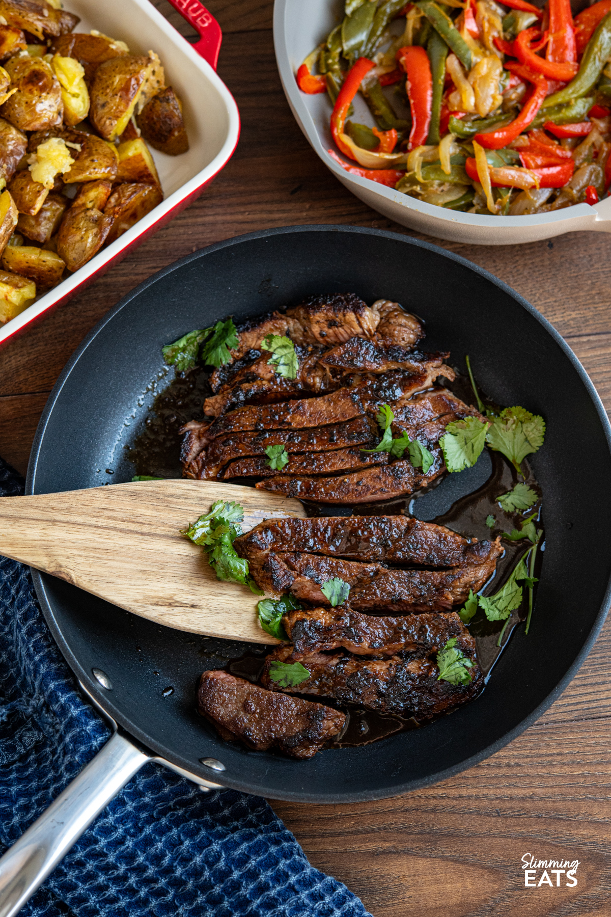 Tender, flavour packed steak marinated in spices and finished with a sweet savory glaze for a simple yet delicious meal. Marinated Mouth Watering Steak in a non stick frying pan with wooden spatula and coriander garnish