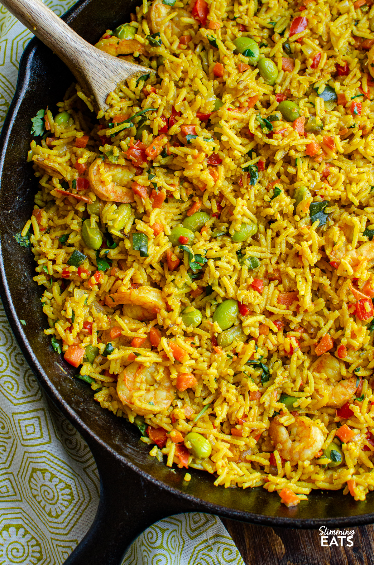 close up of One Pot Prawn and Vegetable Pilaf in skillet with wooden spoon 