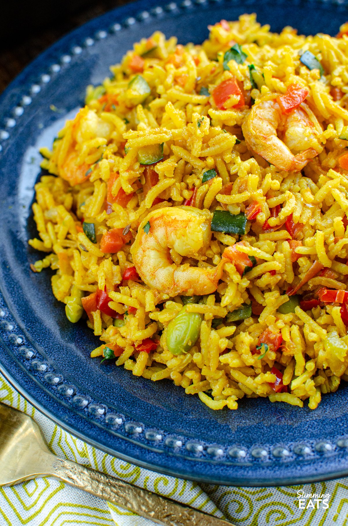 Enjoy the delightful flavours of this one-pan wonder: a delectable Prawn and Vegetable Pilaf that's not only simple but bursting with mouthwatering taste. It's the perfect choice for a quick and satisfying meal, any day of the week. close up of One Pot Prawn and Vegetable Pilaf on navy plate