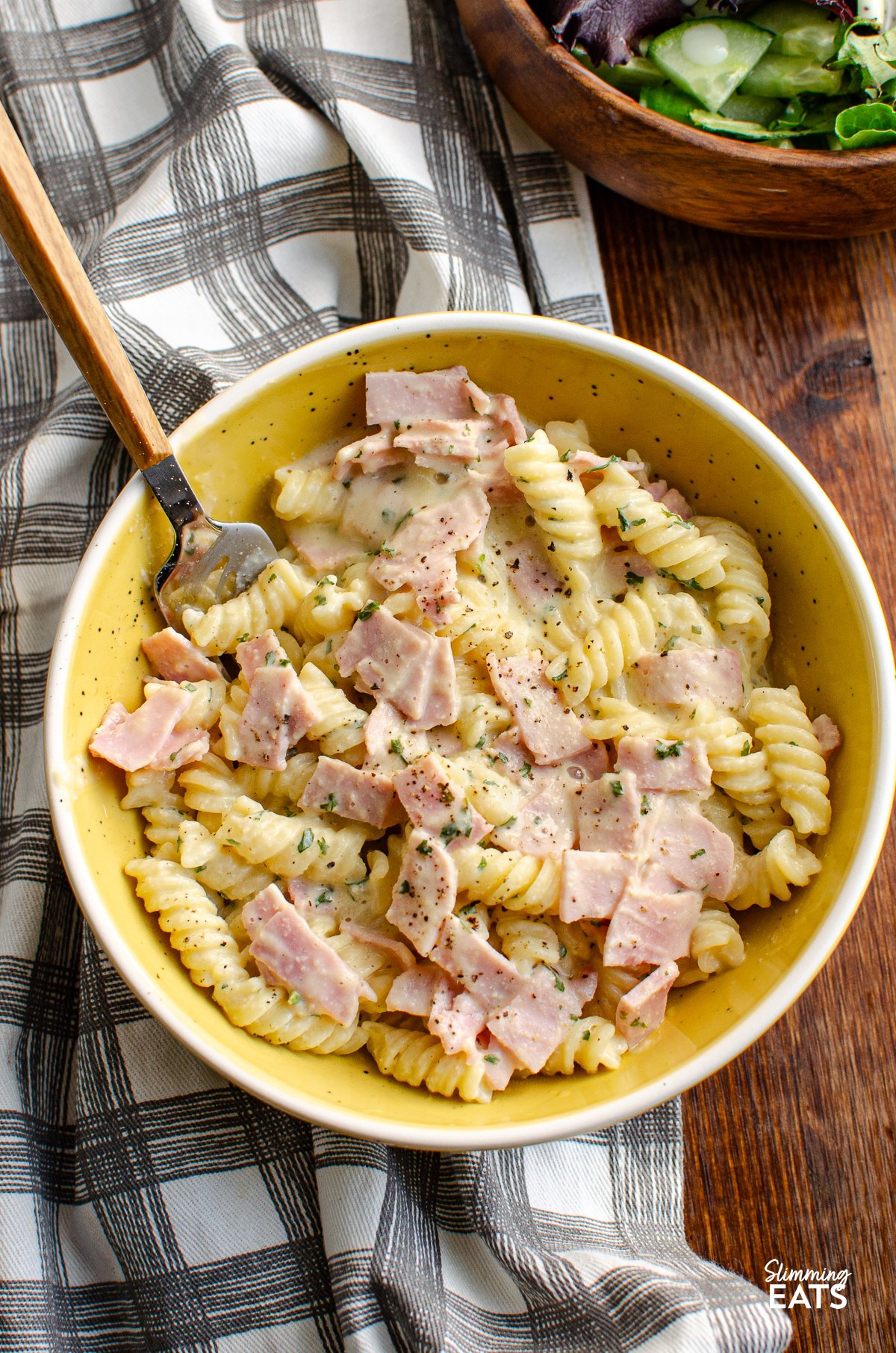 over the top view of Quick Creamy Pasta in white and yellow bowl with fork