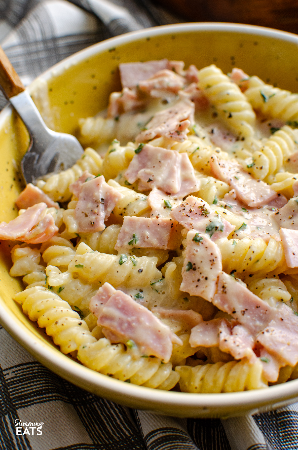 close up of Quick Creamy Pasta in white and yellow bowl with fork