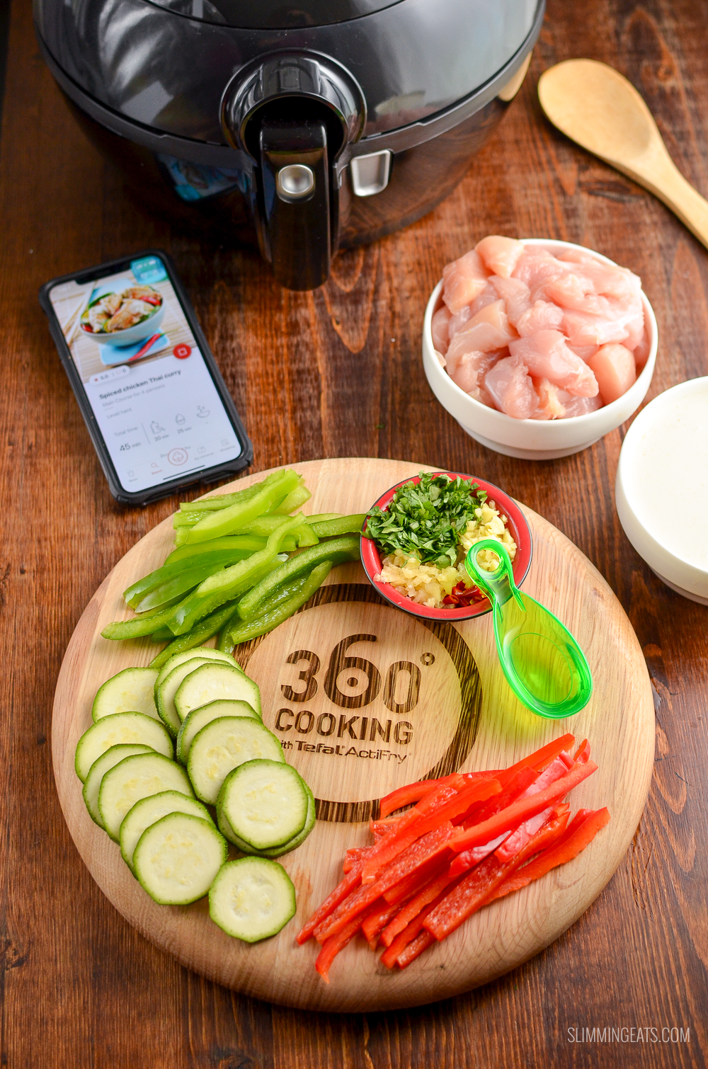 ingredients on a wooden board for Spiced Thai Chicken Curry with Actifry and iPhone displaying recipe